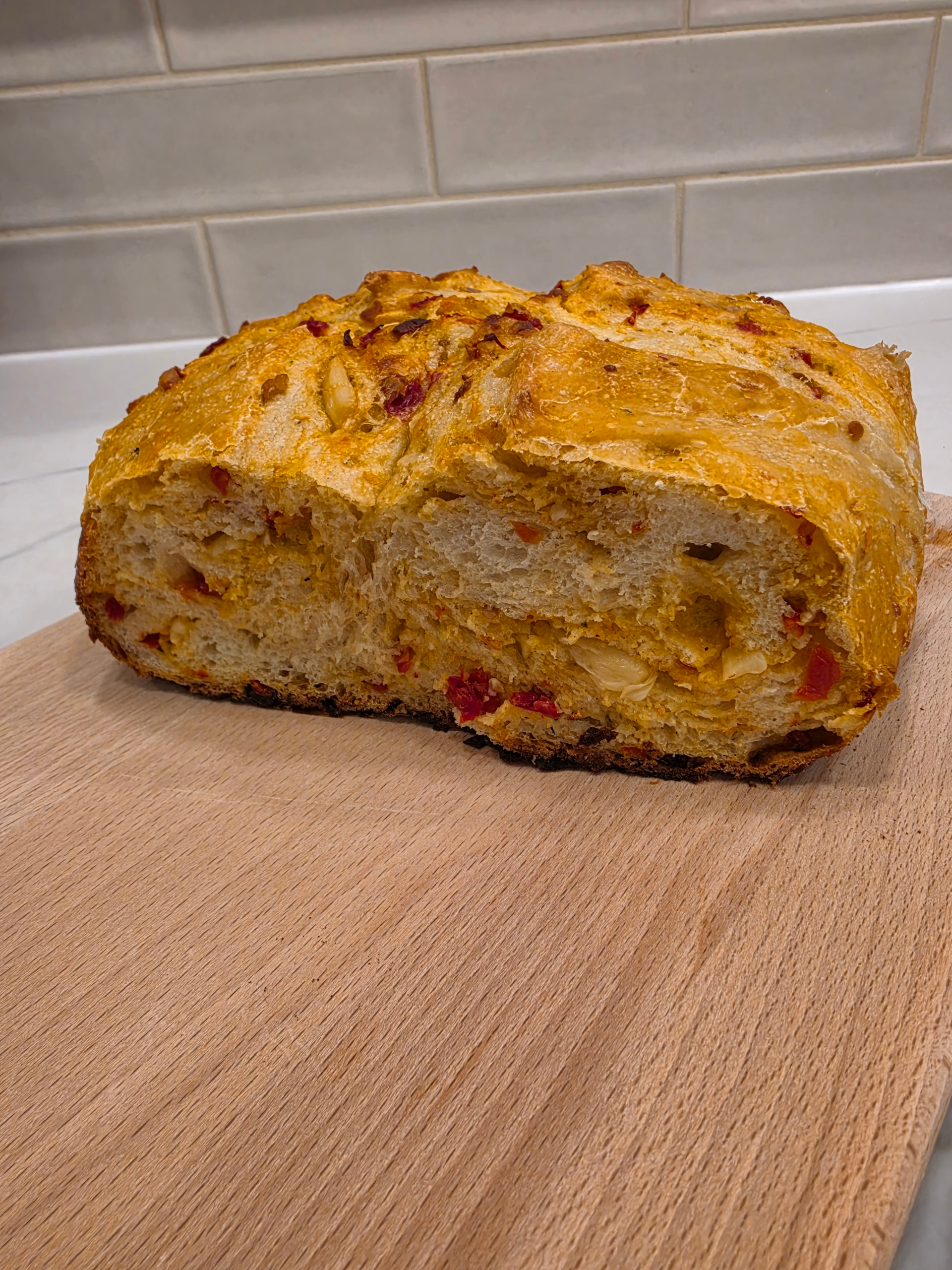 Sourdough bread slice filled with basil pesto, sun-dried tomatoes, and melted mozzarella cheese